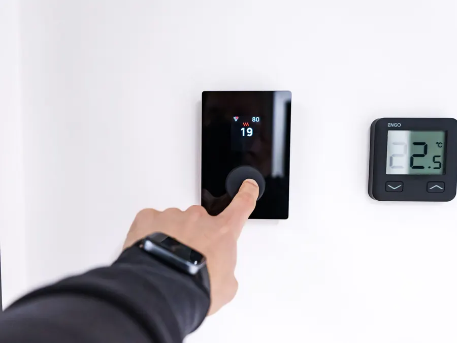 Homeowner adjusting a modern wall thermostat