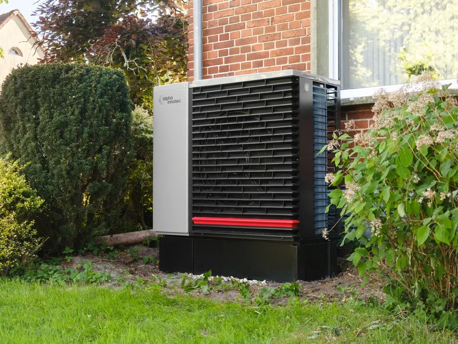 Modern heat pump unit installed outside a brick home